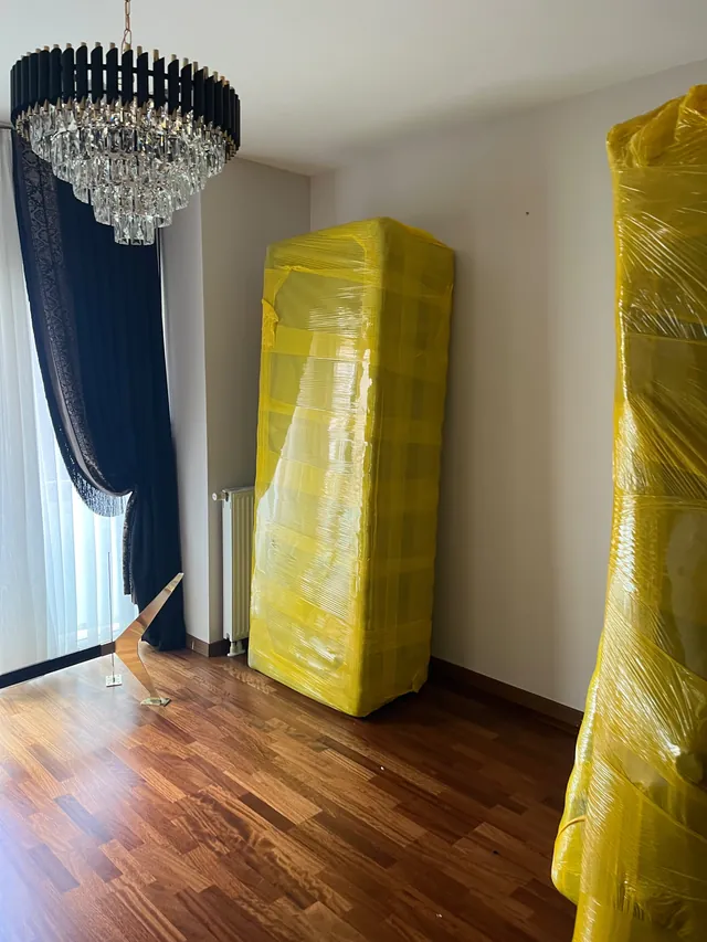 Müşteri evinde sarı koruyucu malzemeyle paketlenmiş mobilyalar